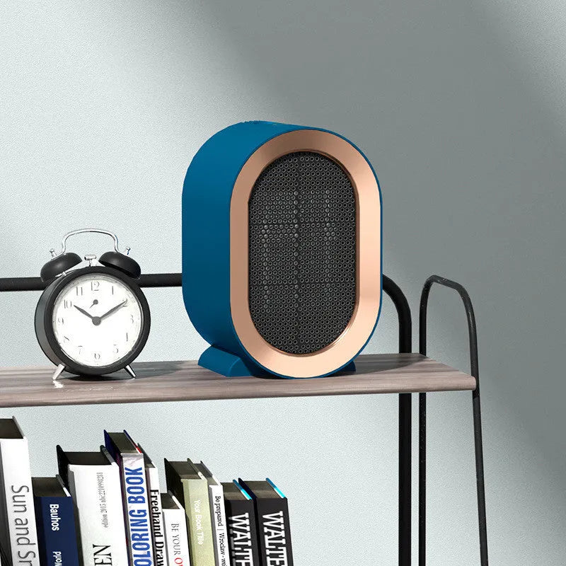 Compact black desktop electric ceramic fan heater with mechanical controls on a wooden desk