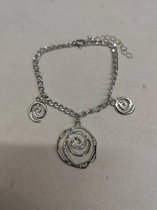 Spiral donut design necklace, bracelet, and ear hook set in gold or silver plating on a dark background.