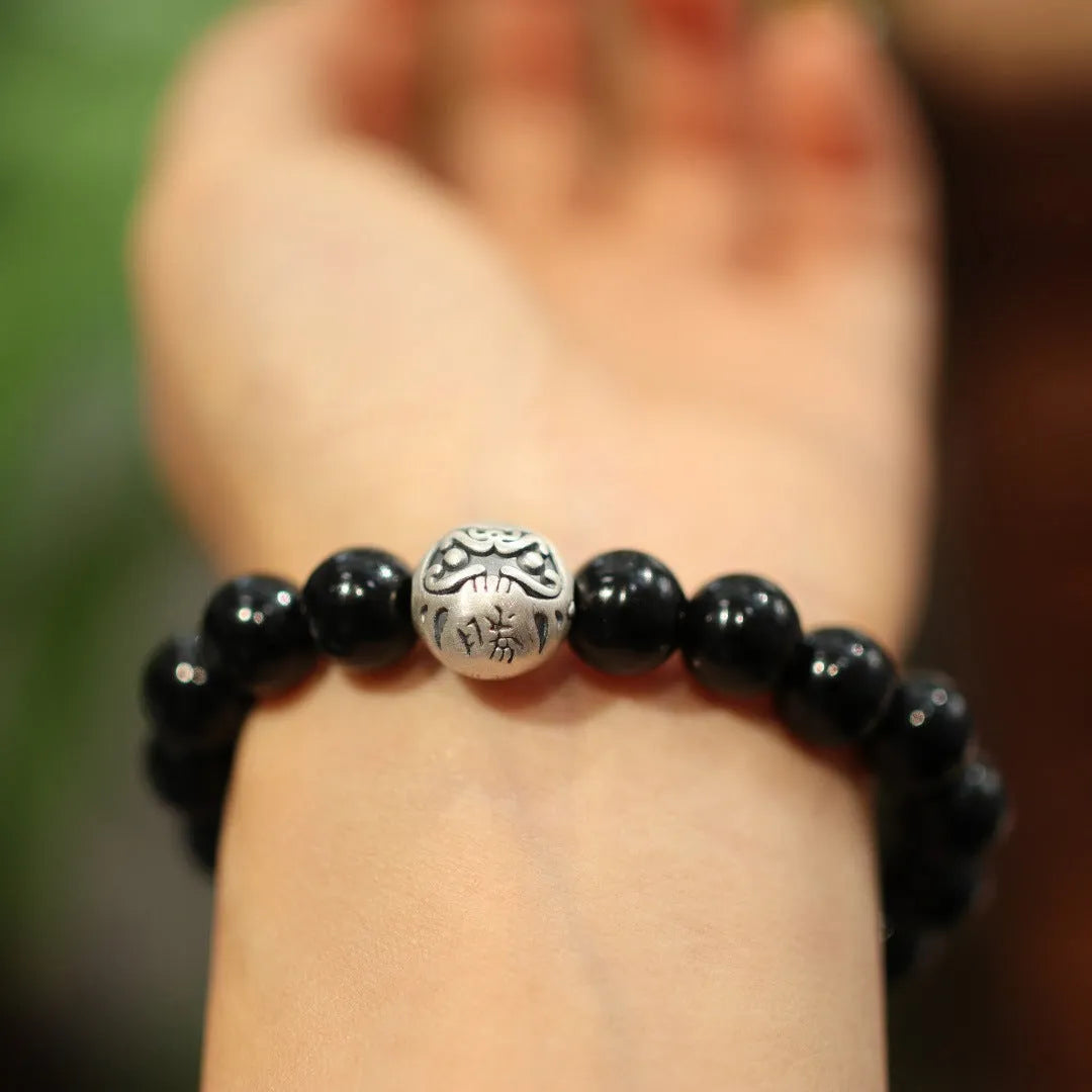 Close-up of a women's bracelet with large black agate beads and sterling silver, showing Chinese style design.