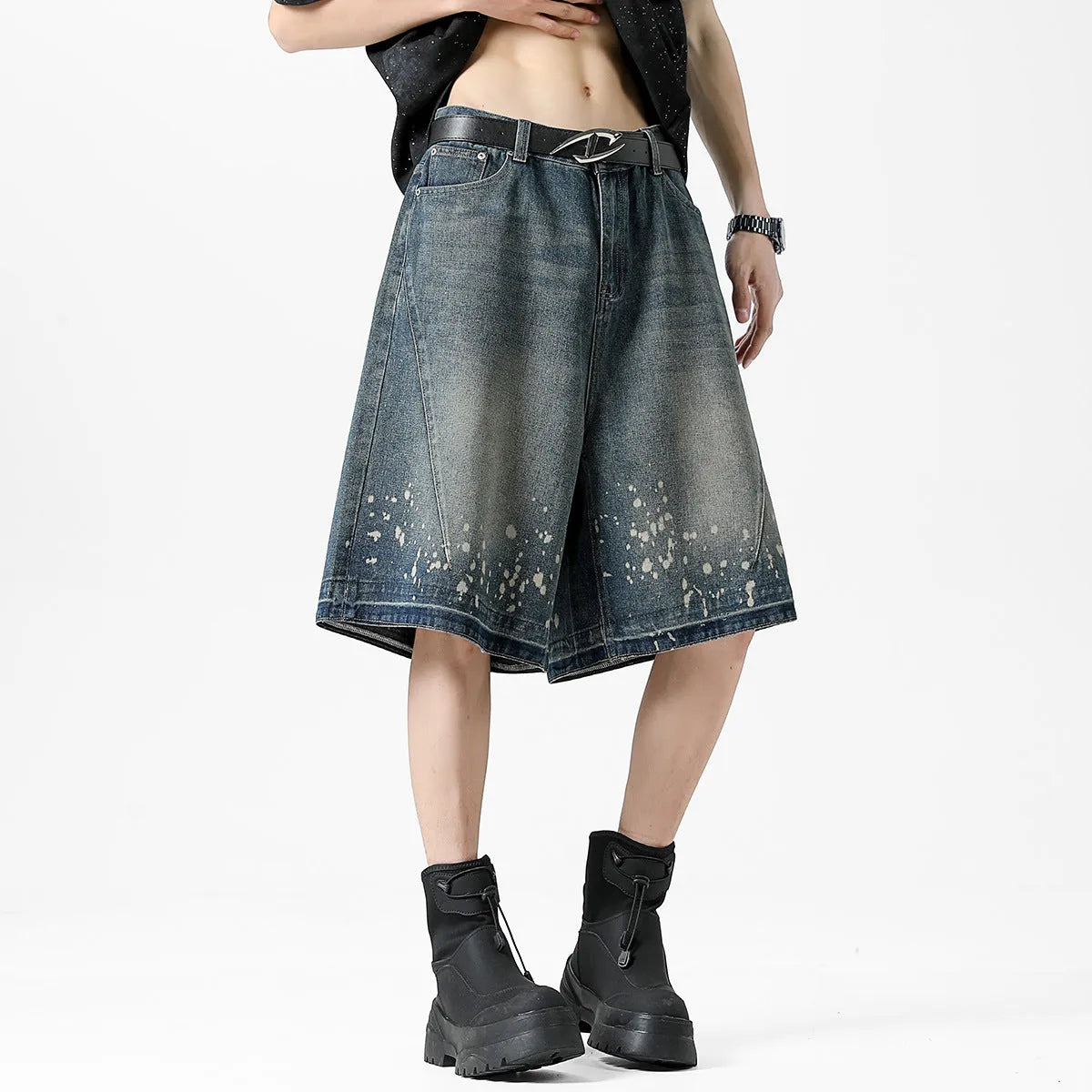 Man wearing retro blue denim shorts with ripped and splash-ink distressing on a straight-leg cut.