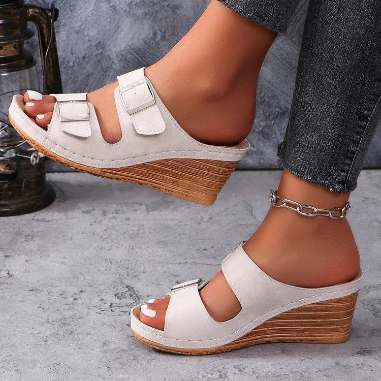 Women's creamy-white beach slippers with an outer wedge belt buckle on a flat rubber sole.