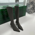 Black women's pointed toe stiletto heel boots with a back zipper, shown below the knee.