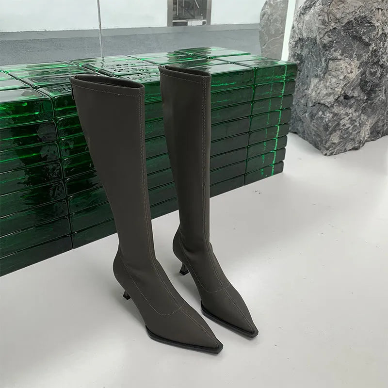 Black women's pointed toe stiletto heel boots with a back zipper, shown below the knee.