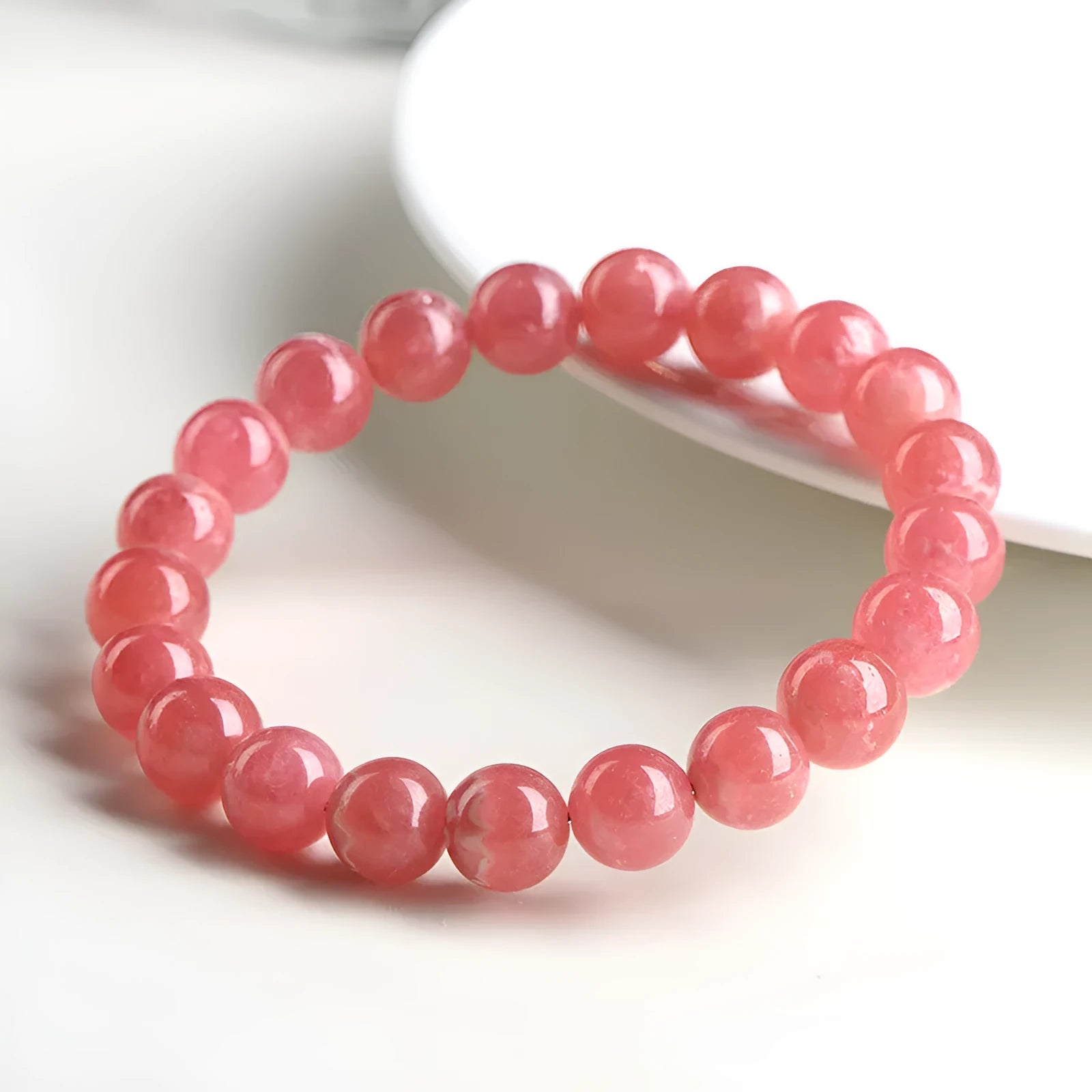 Women's red rhodochrosite crystal bracelet with geometric pattern and longevity lock clasp showing natural stone variations