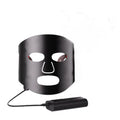 Black and white LED phototherapy face mask with controller for home skin treatment.