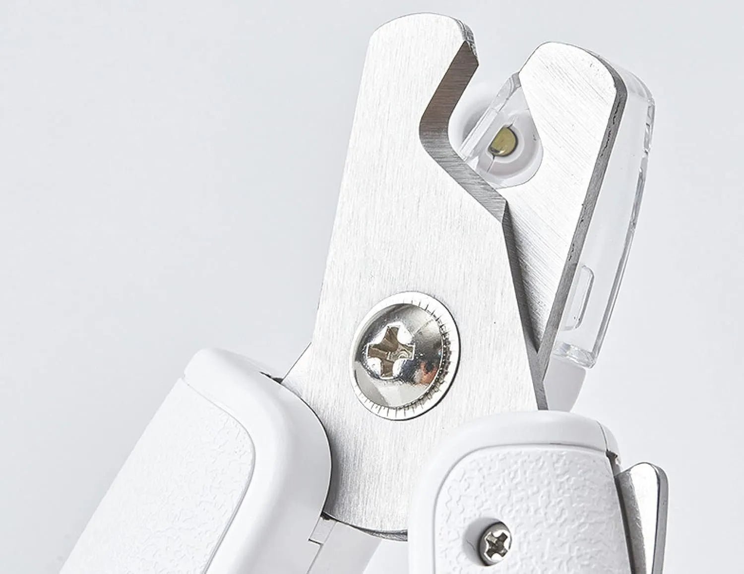 White pet nail clippers with LED light, open transparent splash guard, and separate nail file on a table