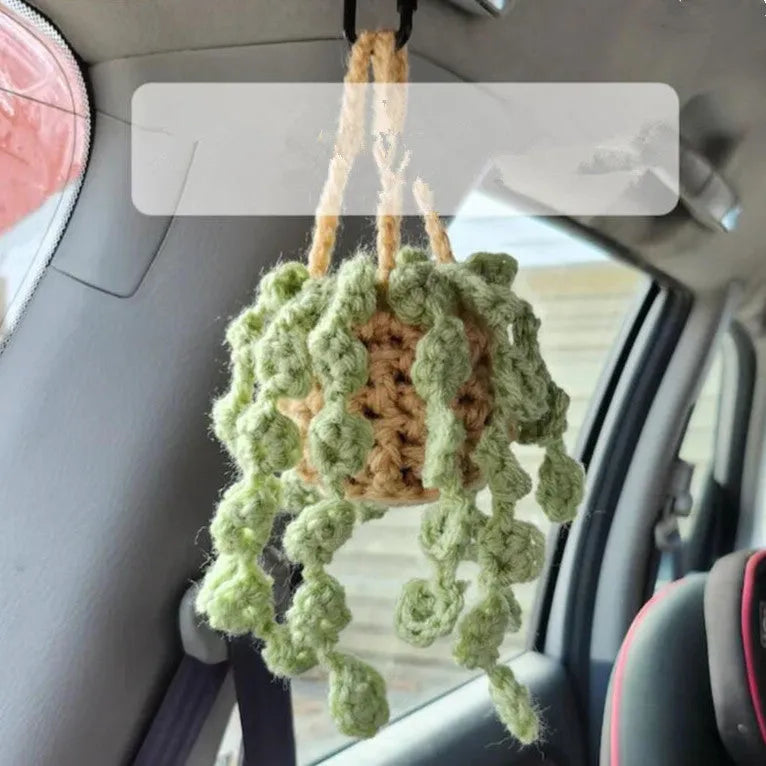 Green and white knitted wool car plant decoration with white hanging rope.