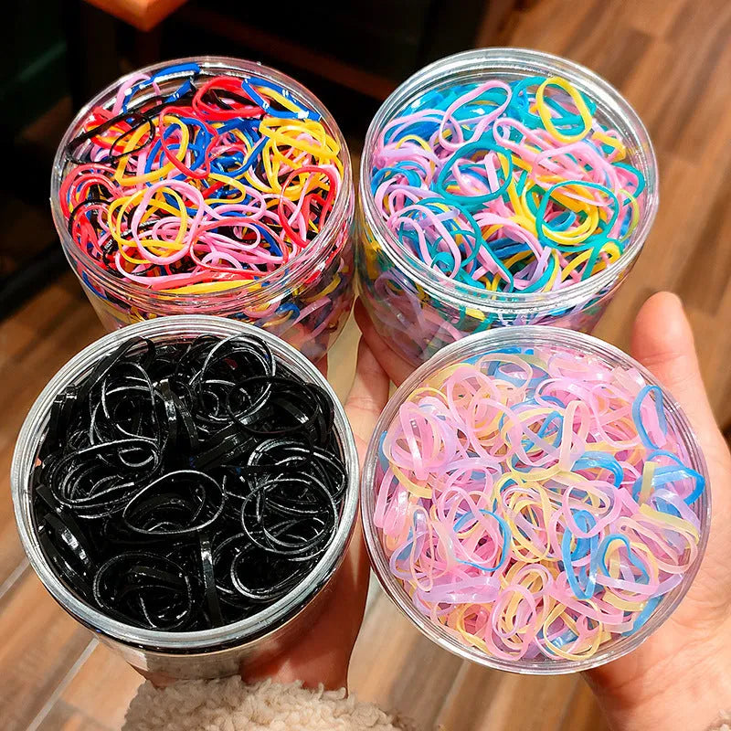 Assortment of colourful thin TPU baby hair ties in a clear reusable plastic container.