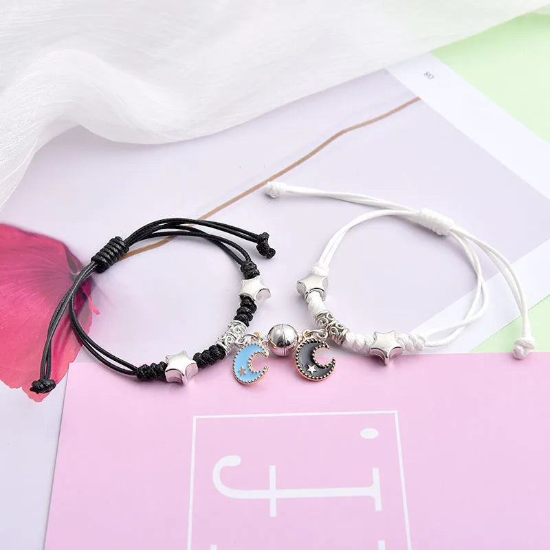 Pair of magnet couple bracelets with suction clasp on wrist, showing alloy designs like crown and love lock.