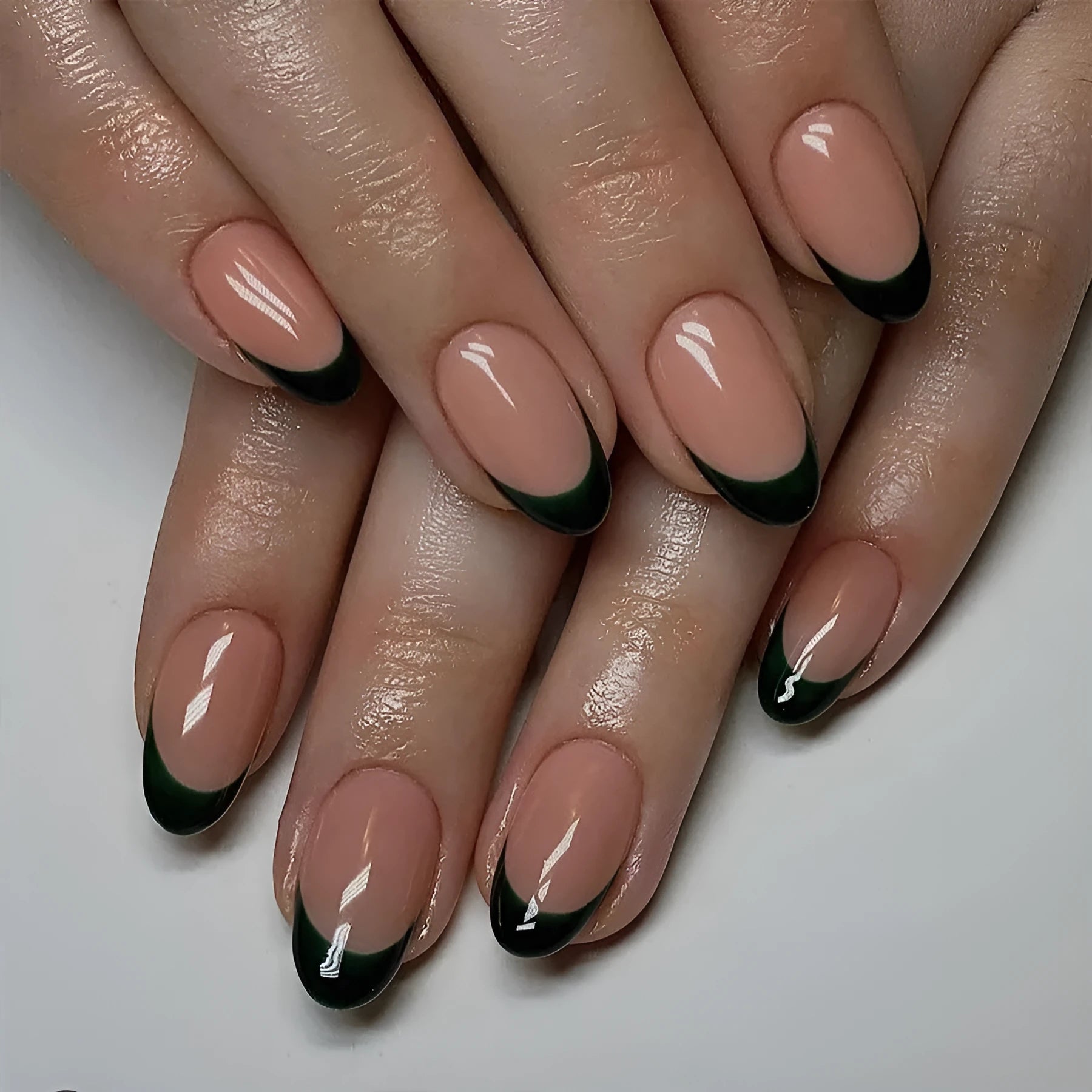 Short almond shaped false nails with black French tips, set of 24 pieces laid out.