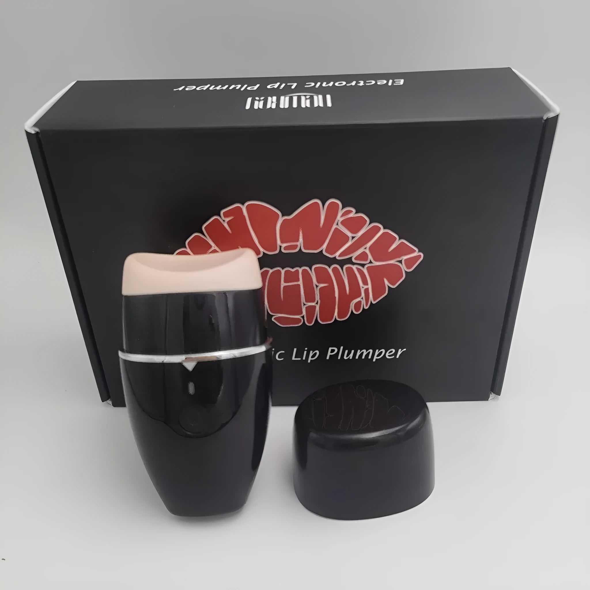Black electric lip plumper device with a silicone tip next to a white USB charging cable.