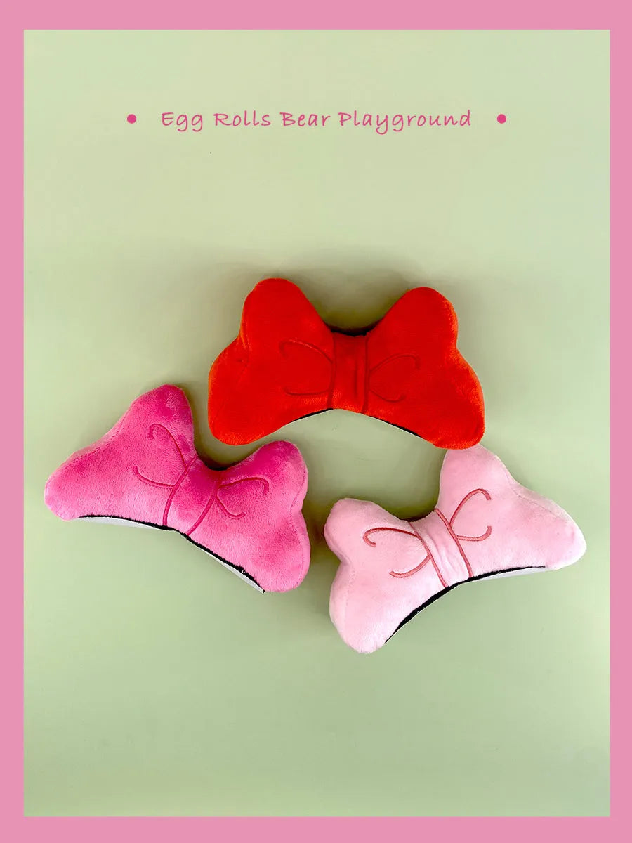 Plush bow tie helmet decoration for motorcycle and ski helmets in red, peach pink, and rose pink colours.