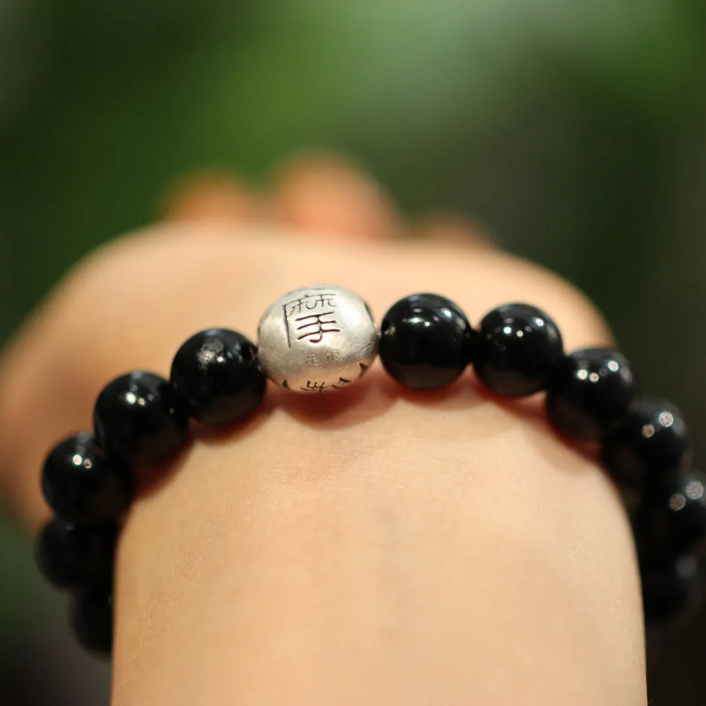 Close-up of a women's bracelet with large black agate beads and sterling silver, showing Chinese style design.