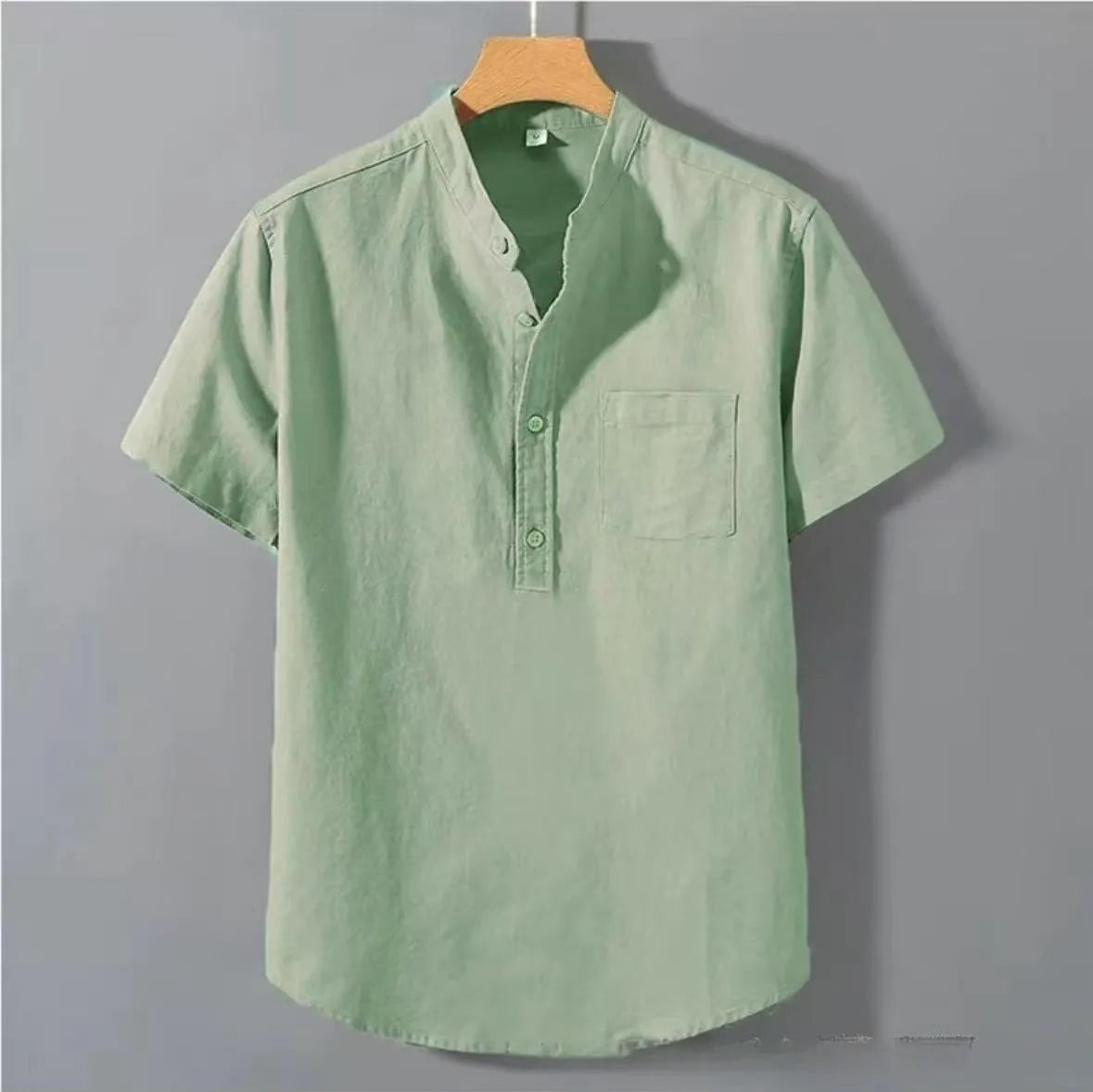 Man wearing a beige loose-fit linen shirt with a stand collar and short sleeves.