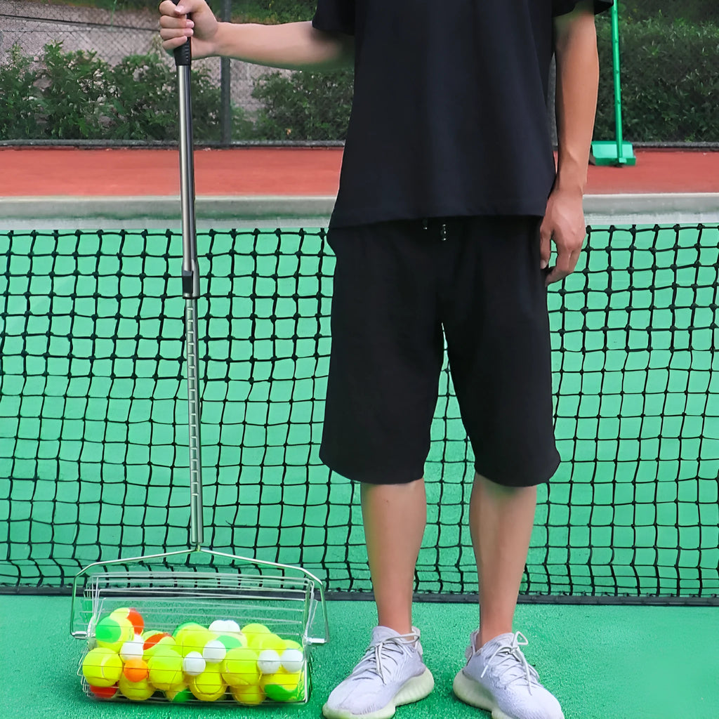Stainless steel tennis ball roller picker with adjustable width on a court.