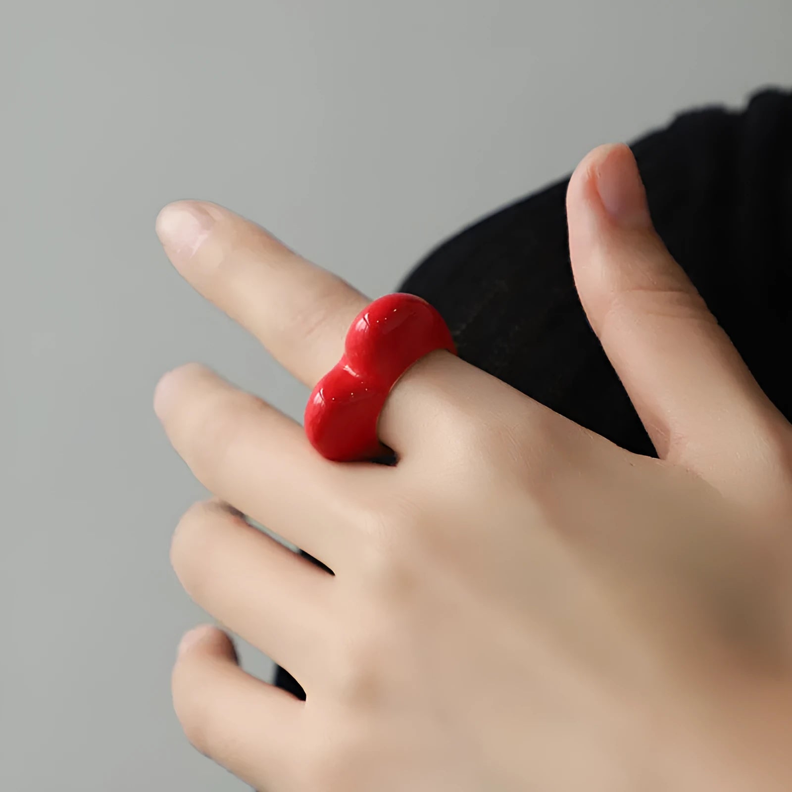 Close-up of a heart-shaped ring with a raised red enamel heart on a metallic band.