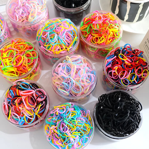 Assortment of colourful thin TPU baby hair ties in a clear reusable plastic container.