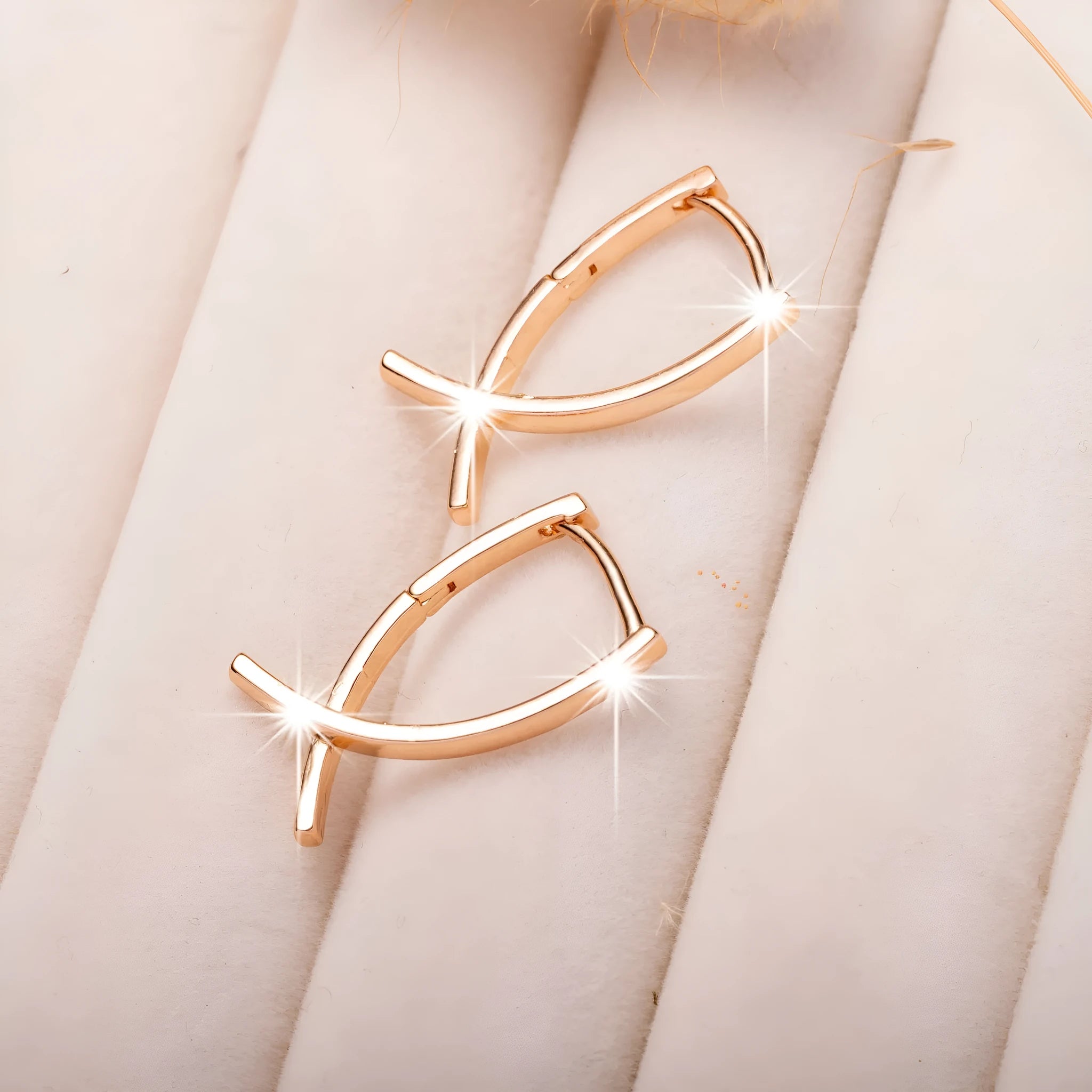 A pair of rose gold coloured cross-shaped earrings on a white background.