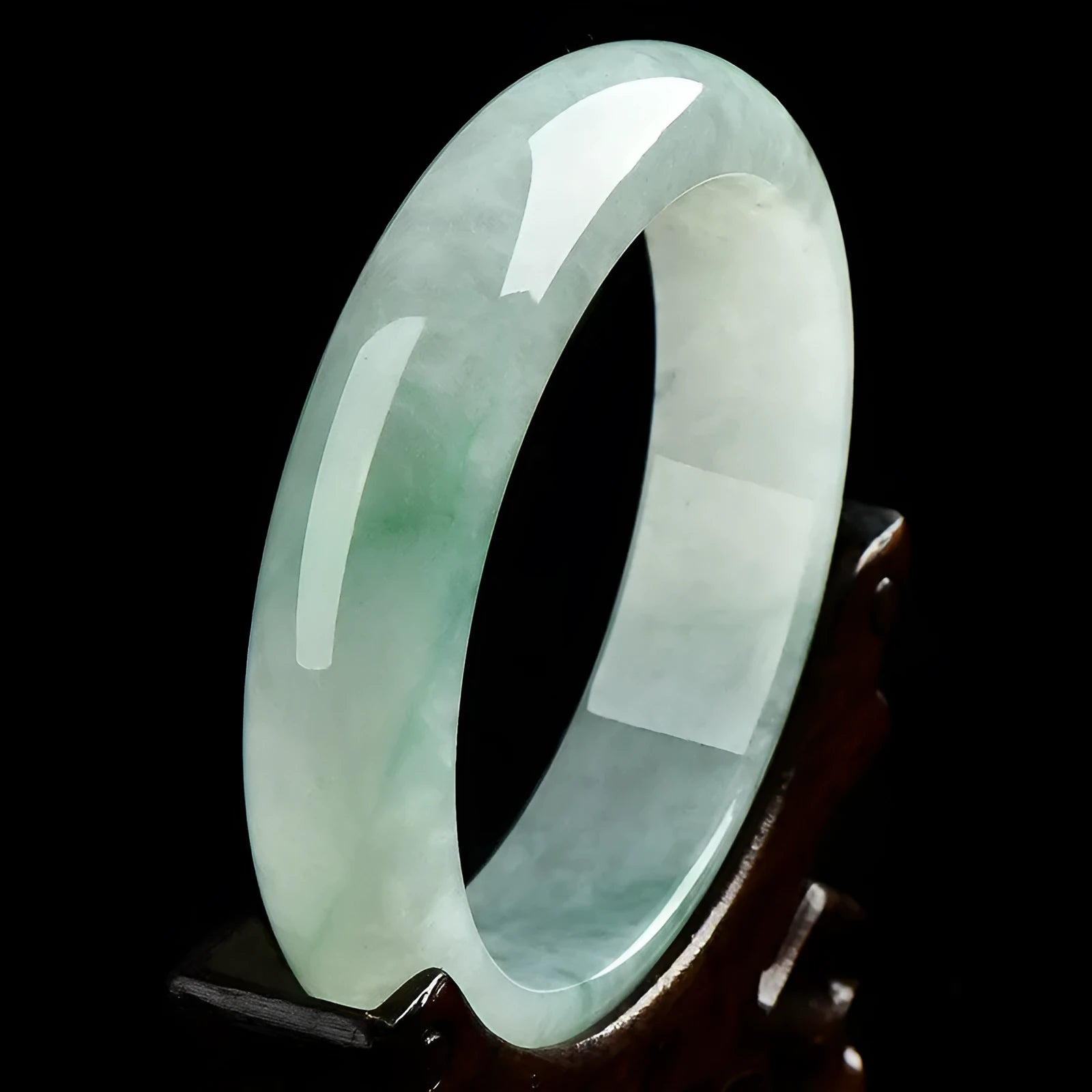Light green polished jade bracelet in a natural style on a wrist.