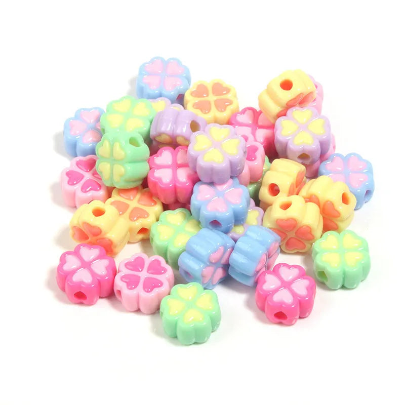 A pile of 15mm frosted acrylic four-leaf clover beads in mixed colours including pink, green, and blue.