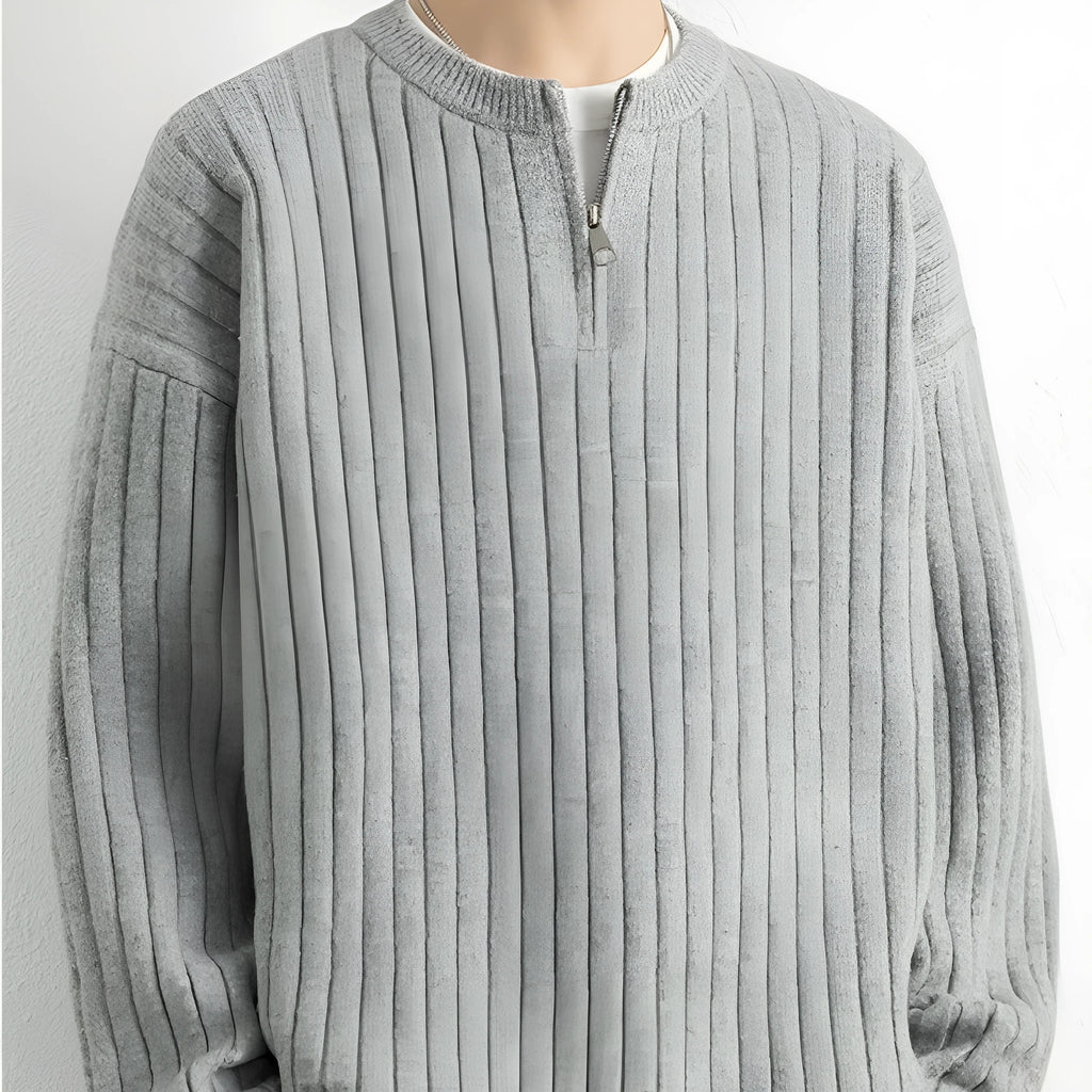 Man wearing a grey half-zip loose knit sweater, showing the textured fabric and front zip.