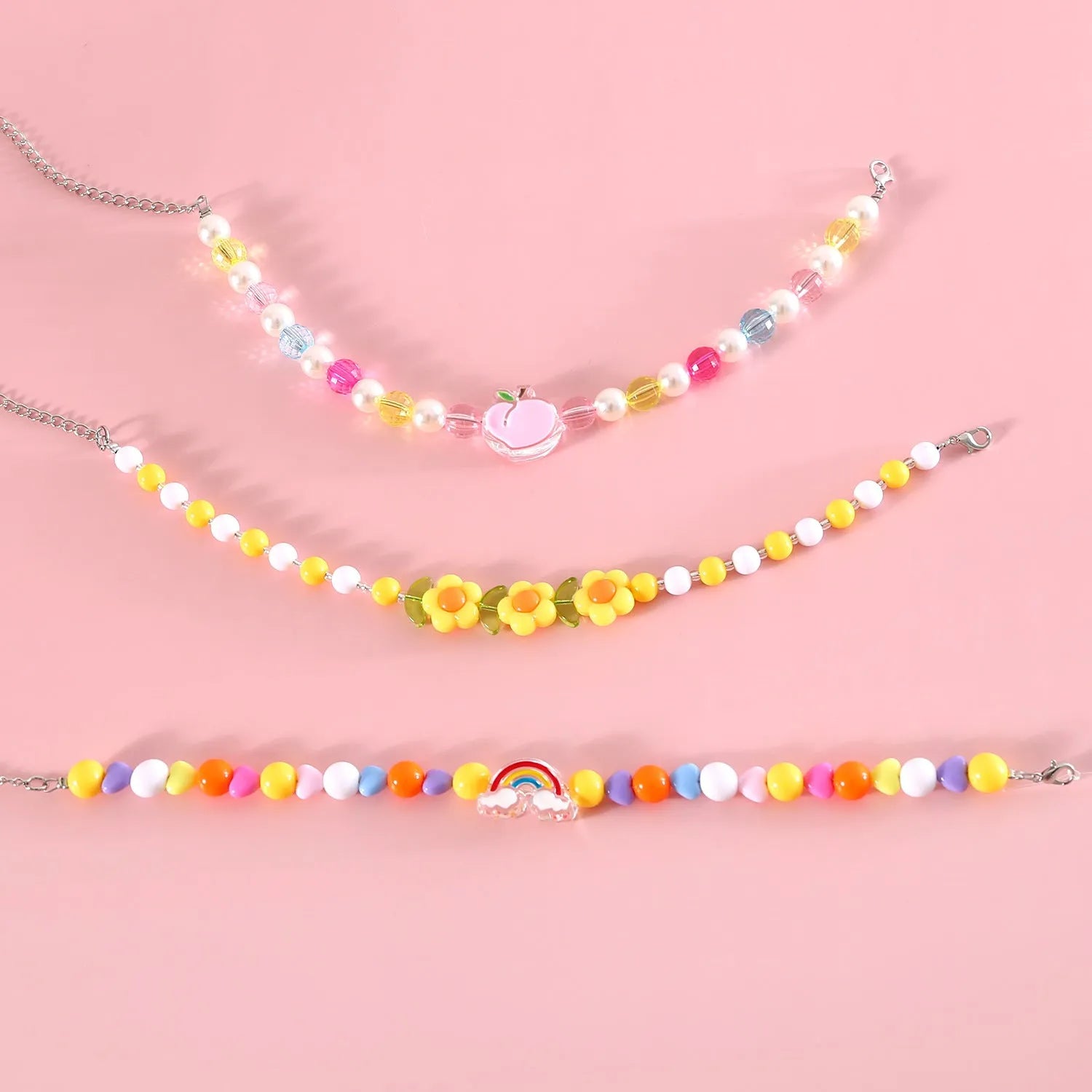 Colourful plastic pearl bead cat necklace with small flower, rainbow, or peach designs on a white background.