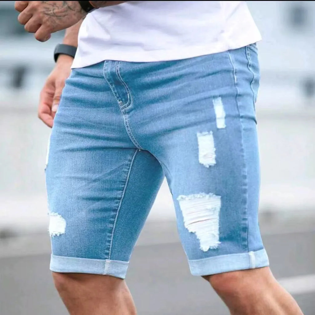 Sky blue denim shorts with multiple distressed holes and straight leg silhouette