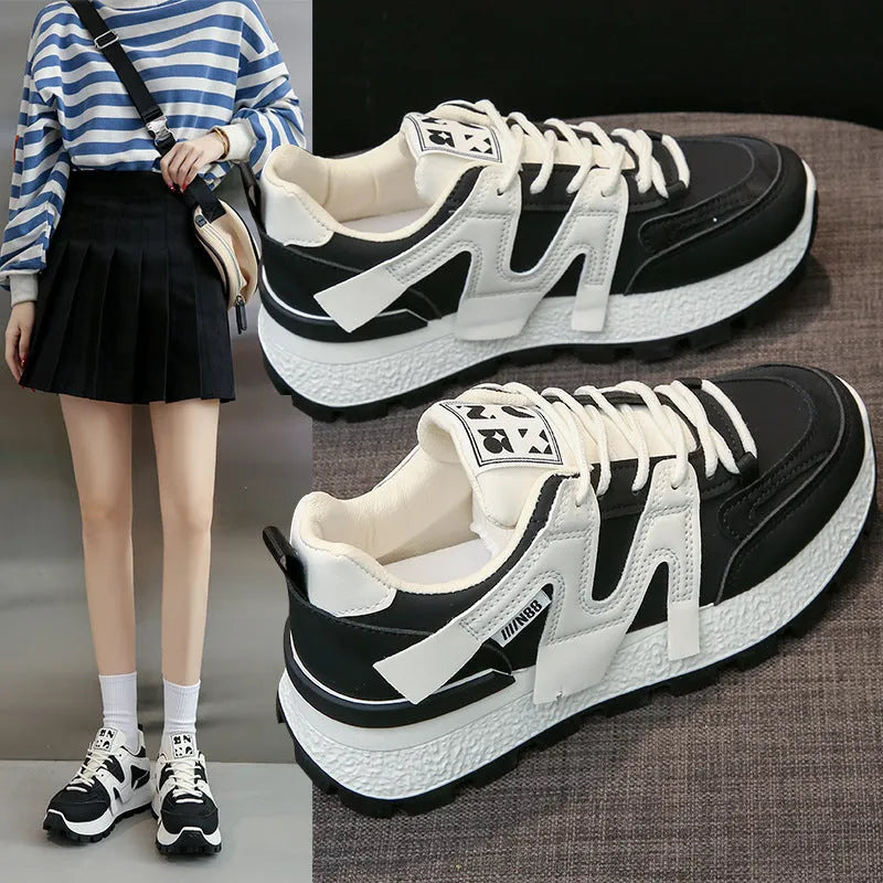 A pair of low-top black or white sneakers with a round toe, lace-up front, and flat rubber sole.
