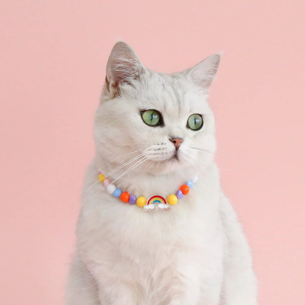 Colourful plastic pearl bead cat necklace with small flower, rainbow, or peach designs on a white background.