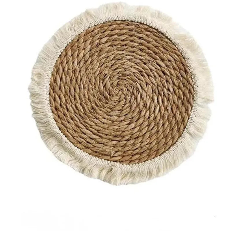 Round natural papyrus placemat with corn rope tassel trim on a wooden table.