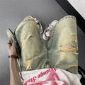 Men's blue denim shorts with yellow mud wash effect, ripping details, button fly, and loose straight-leg fit
