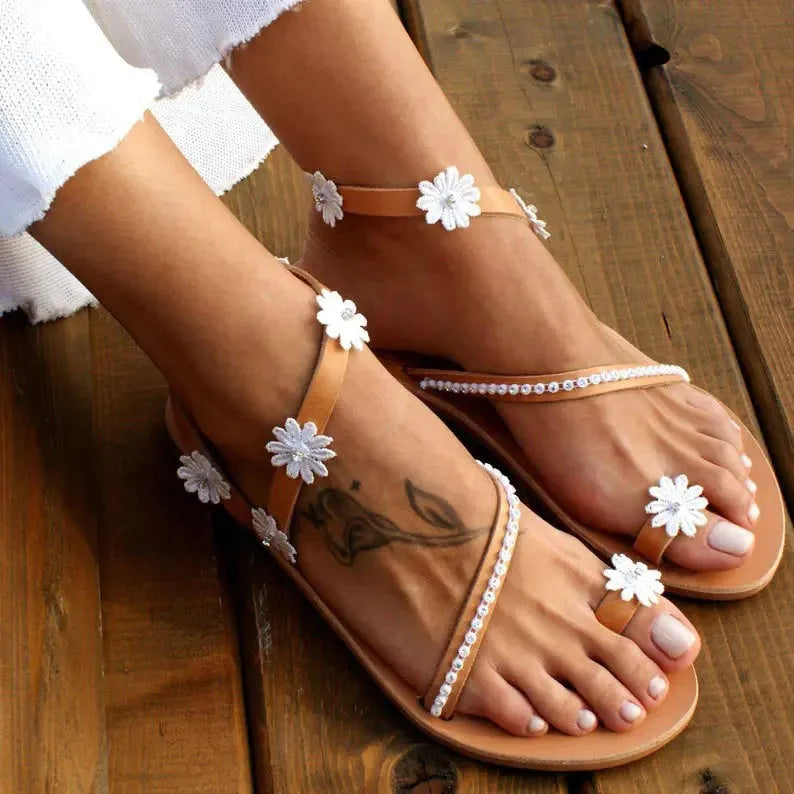Brown women's flat Roman sandals with floral ethnic pattern and herringbone toe design on rubber sole.