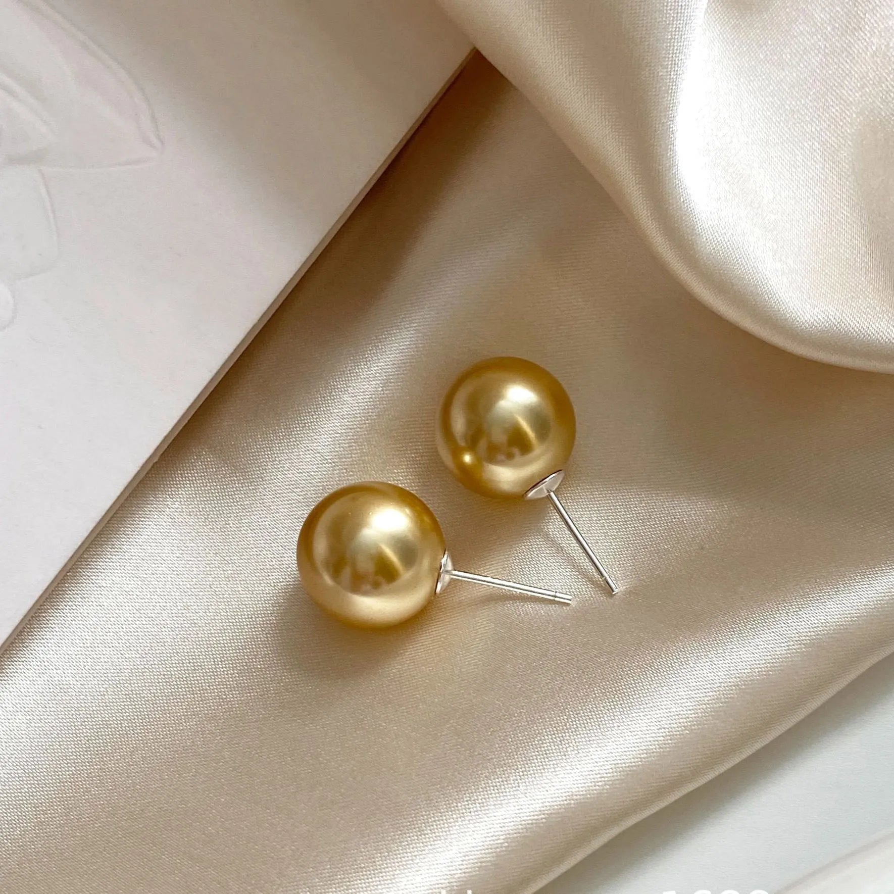 A pair of large geometric pearl stud earrings for women in silver, showing an eight-point star design detail.