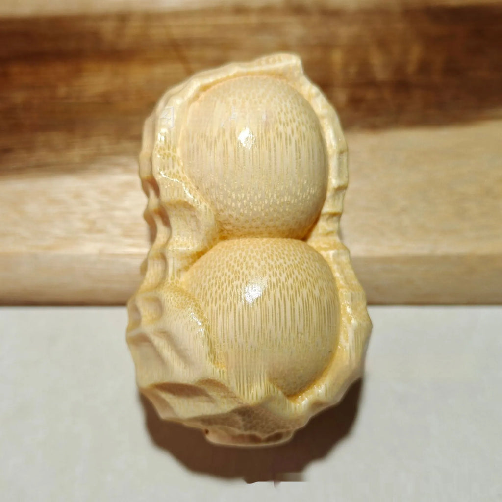 Carved solid bamboo peanut ornament in a modern simplicity style on a plain background.
