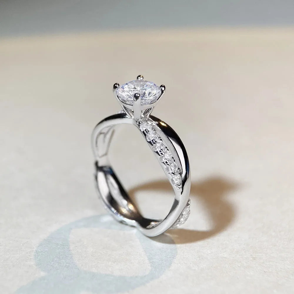 Silver moissanite ring with twisted arm band and four-claw setting holding 1 karat stone