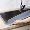 Thick grey silicone kitchen sink water blocking plate sitting on a counter next to a sink
