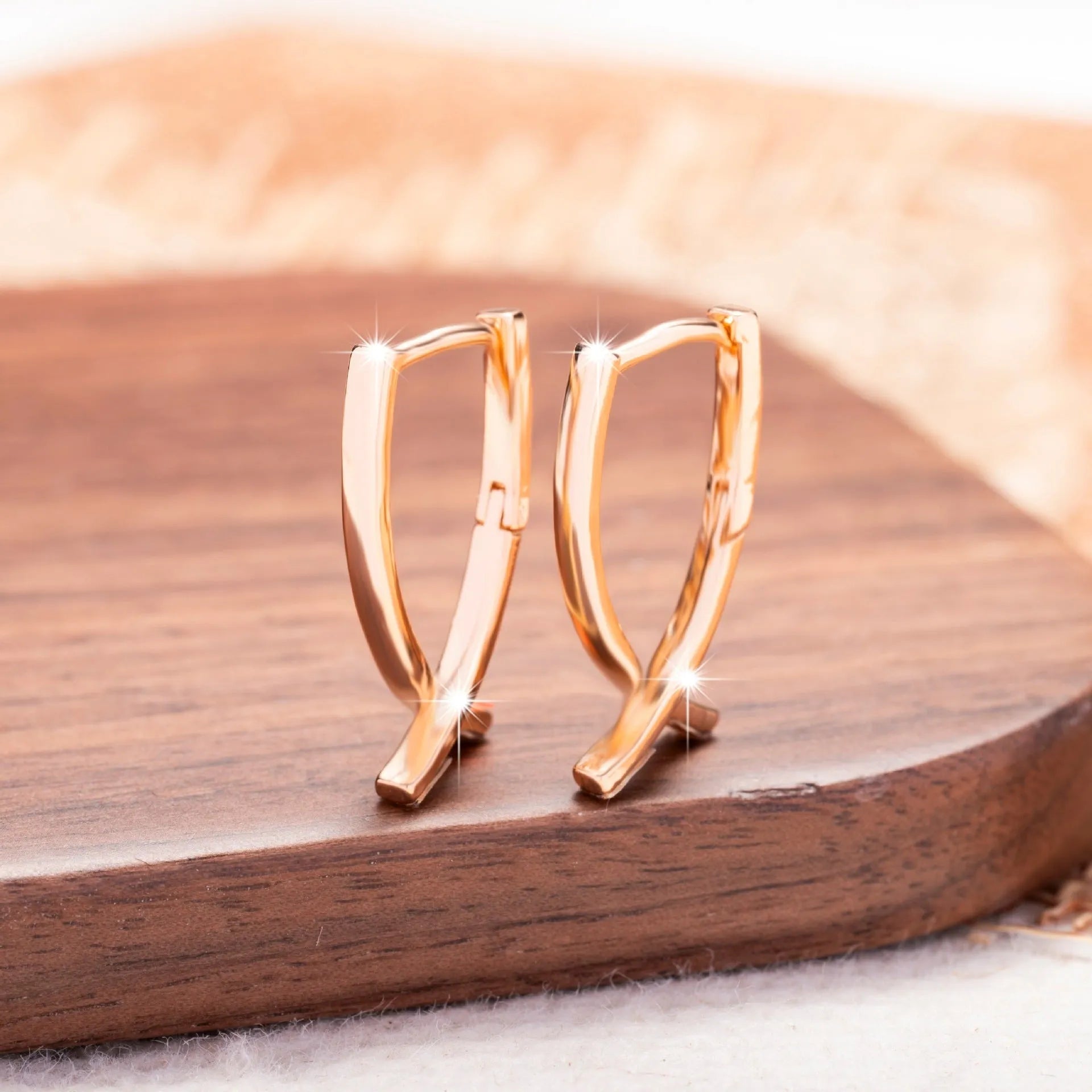 A pair of rose gold coloured cross-shaped earrings on a white background.
