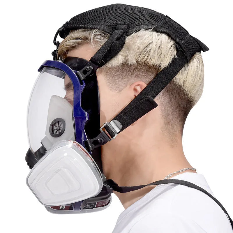 Blue edge spherical full face gas mask with trapezoidal canister on a grey background.