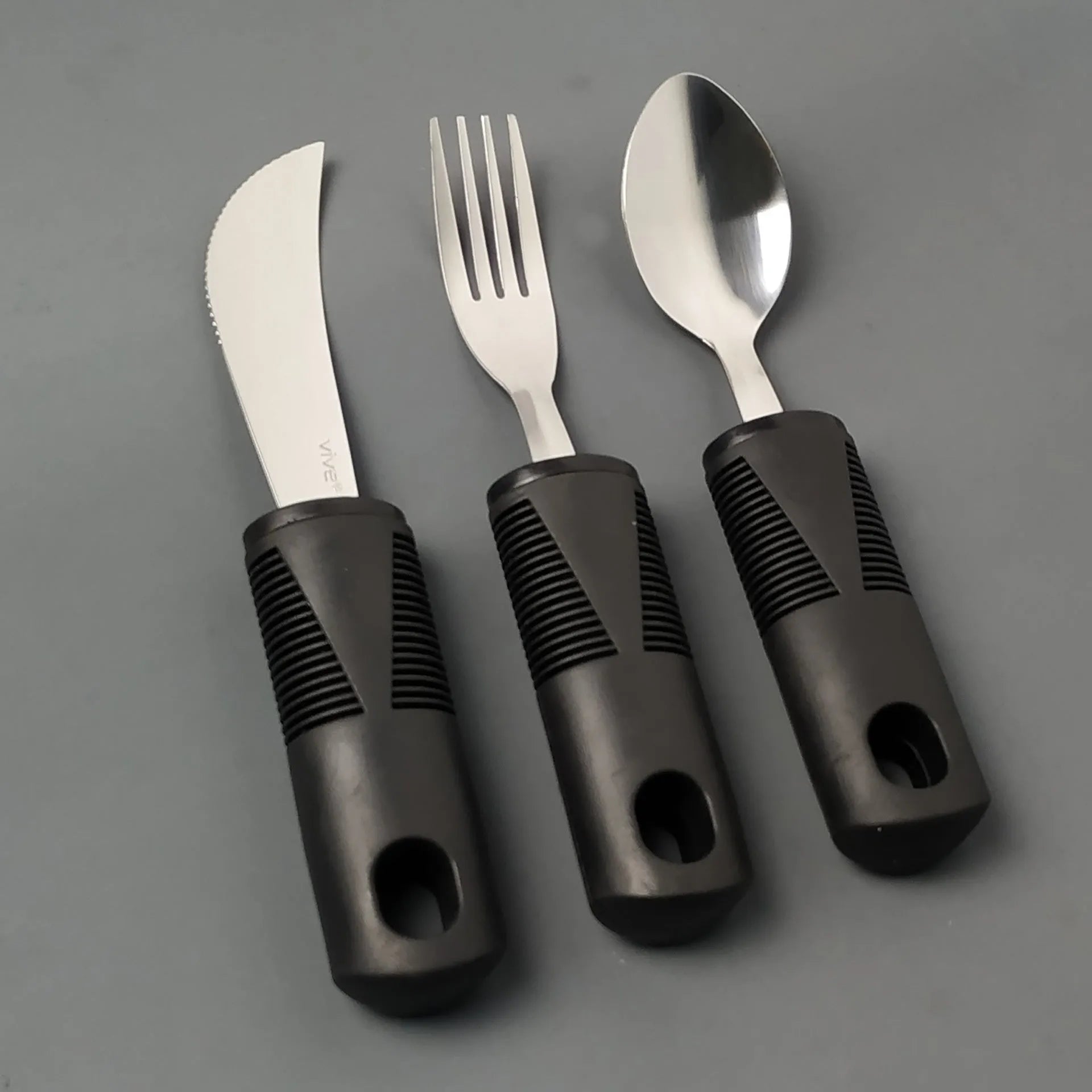 Stainless steel adaptive spoon with black rubber anti-shake handle for elderly food aid.