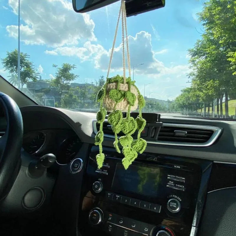 Green and white knitted wool car plant decoration with white hanging rope.