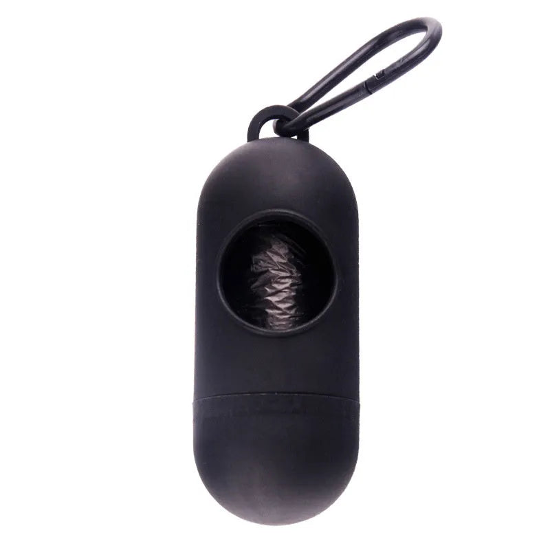A small black plastic dog poop bag holder with a hook and Velcro strap, shown next to a roll of bags.