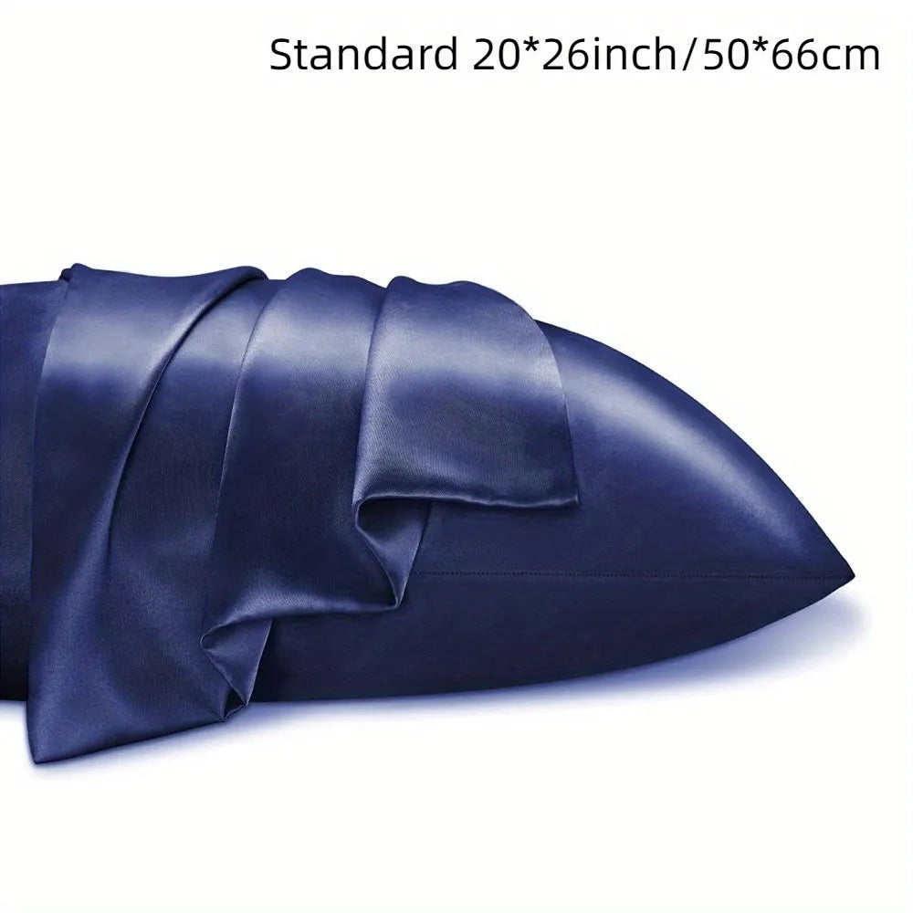 Pair of solid colour satin pillowcases in polyester fabric on a bed.