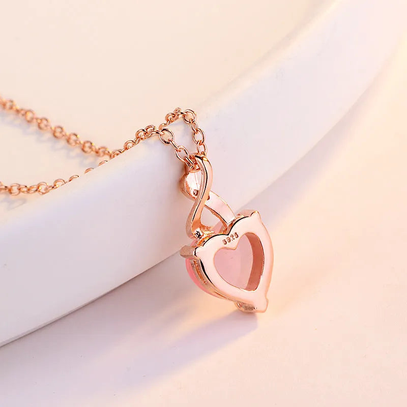 Rose gold heart-shaped pendant necklace with a pink synthetic crystal centre on a matching cross chain.