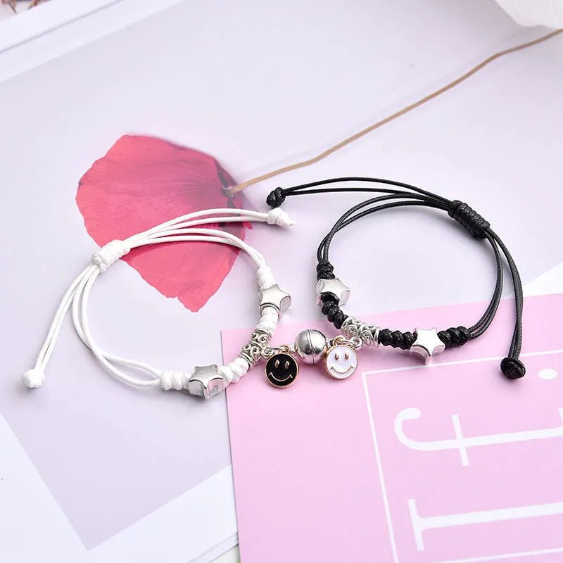 Pair of magnet couple bracelets with suction clasp on wrist, showing alloy designs like crown and love lock.
