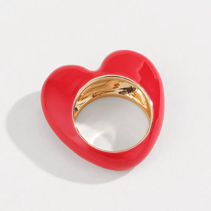 Close-up of a heart-shaped ring with a raised red enamel heart on a metallic band.