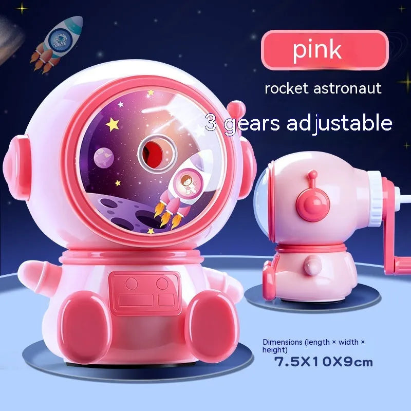 Blue and pink cartoon astronaut model manual pencil sharpener for children on a desk.