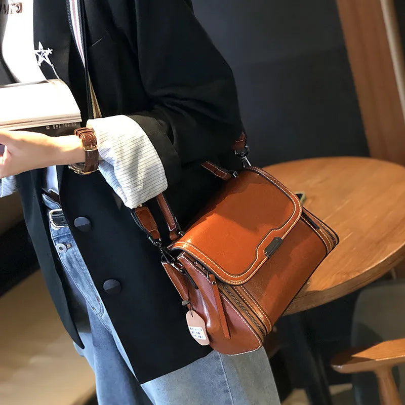 Women's brown genuine oil wax leather messenger bag with double strap and external pocket.