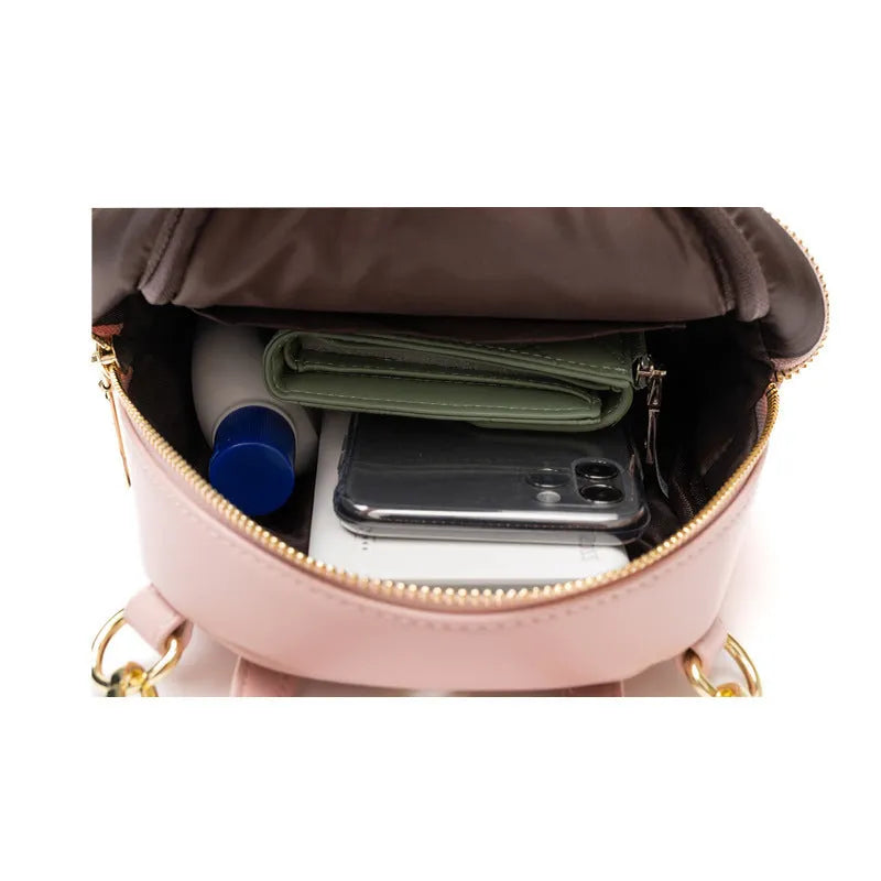 Soft black PU mini backpack with front pockets, shown open to reveal internal mobile phone sleeve and zipper compartment.