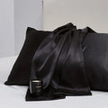 Pair of solid colour satin pillowcases in polyester fabric on a bed.
