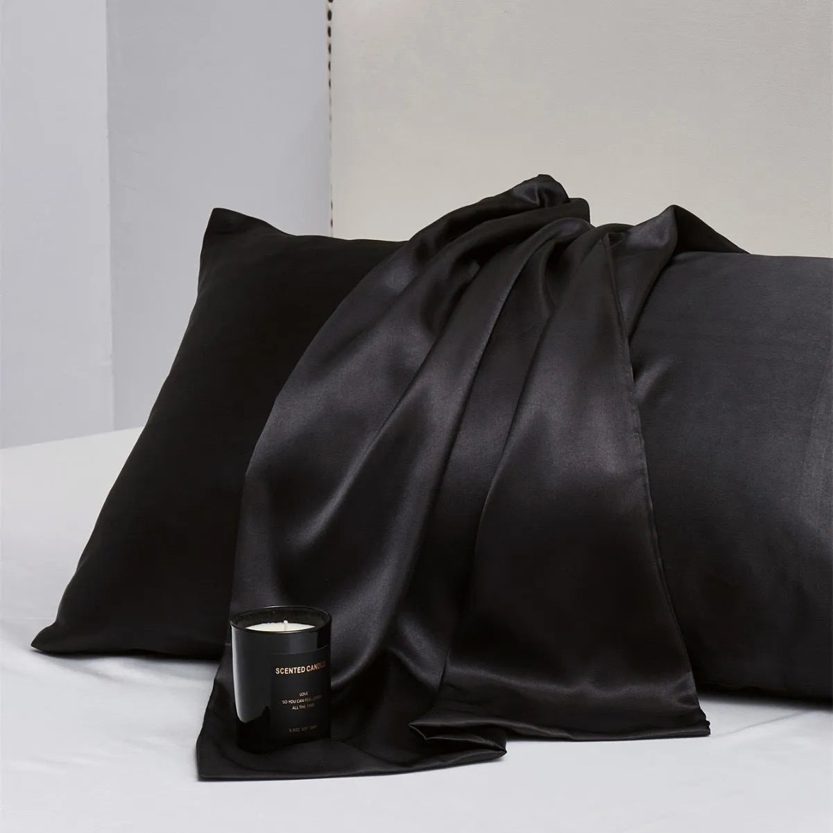 Pair of solid colour satin pillowcases in polyester fabric on a bed.